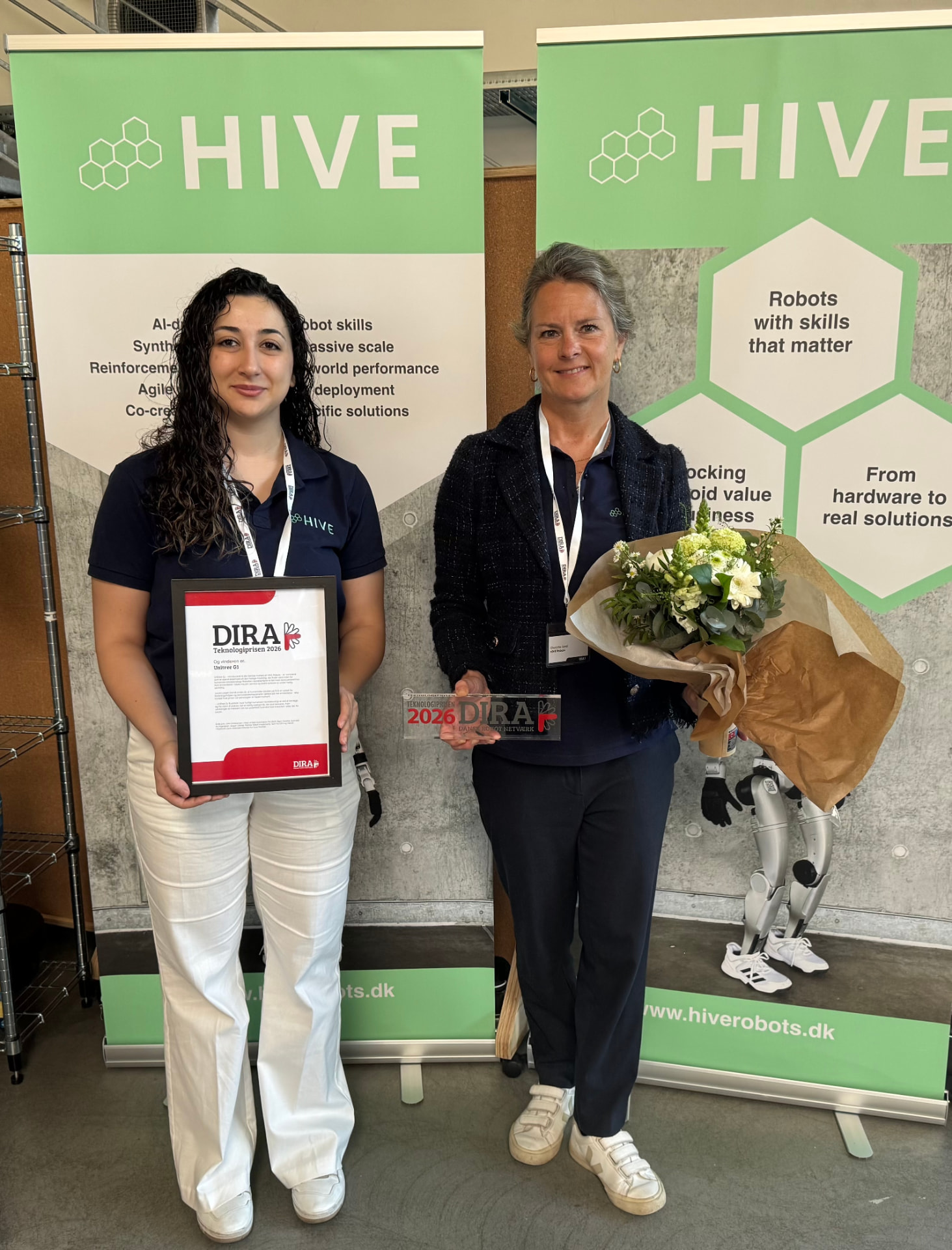 Eymen and HIVE CEO Charlotte Sand holding the DIRA Teknologiprisen 2026 diploma and trophy in front of HIVE Robots banners